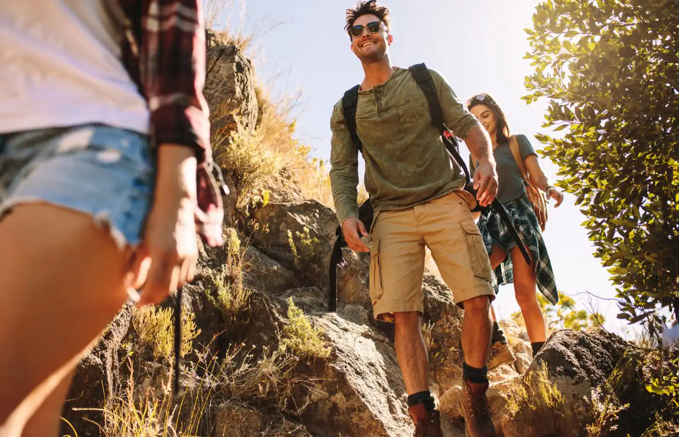 Groupe d'amis en randonnée sur un sentier de montagne ensoleillé, profitant de la nature et du plein air.